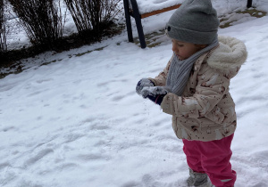 dziewczynka patrzy na śnieg na swoich rękach